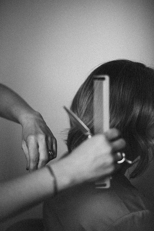 Hands holding salon scissors and comb, working on a client’s hair