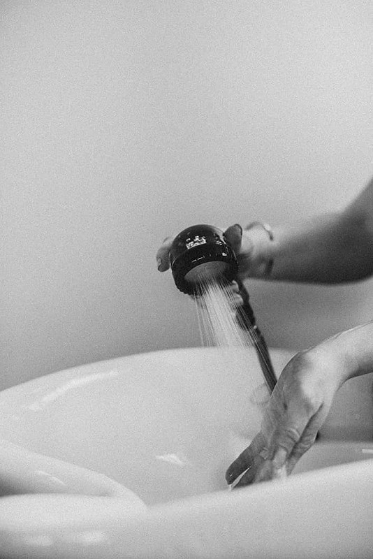 Hands testing water temperature at a salon basin sink